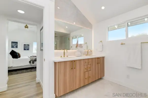 Primary bathroom with oak double vanity and brass fixtures