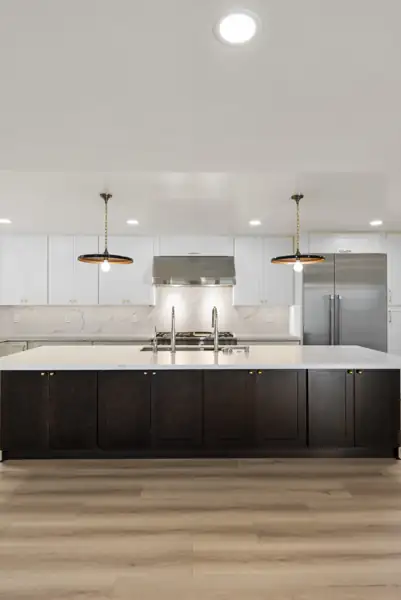 Del Cerro: Kitchen with dark island, white cabinets and quartz backsplash