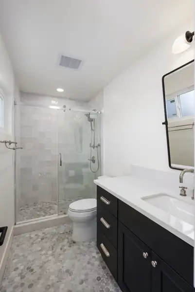 Bathroom with black vanity and tiled glass shower