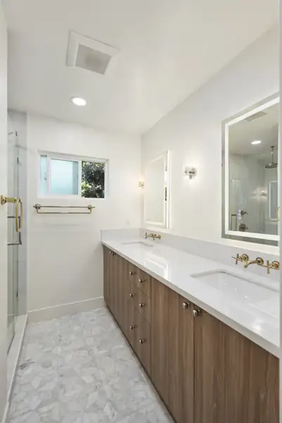 Bathroom with walnut double vanity and brass fixtures