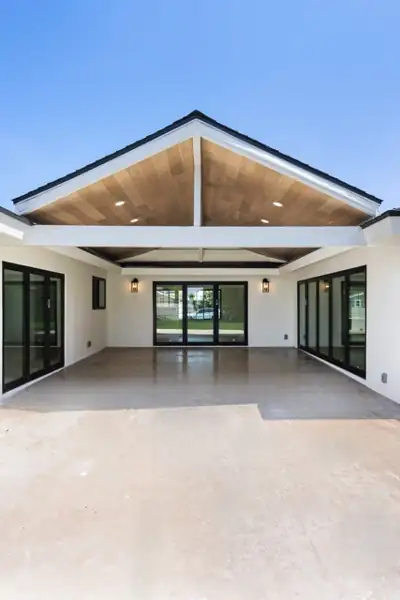 Covered patio with vaulted wood ceiling and black-framed doors