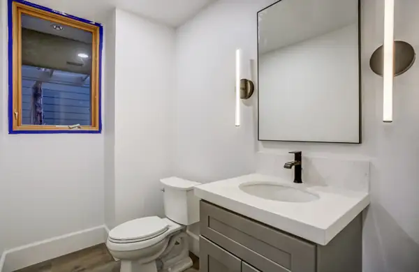 Powder room with gray vanity and vertical sconces