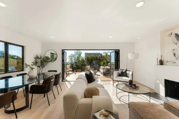 Living and dining room with folding glass doors open to the deck