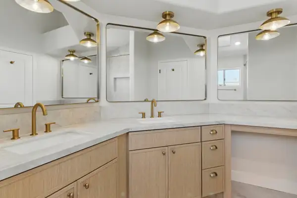 Corner double vanity with brass-framed mirrors