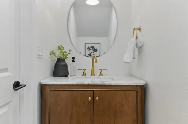 Powder room with walnut vanity and oval mirror