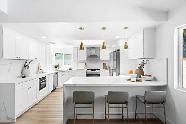 White kitchen with waterfall peninsula and brass pendants