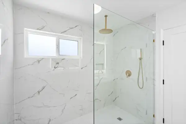 Marble-look walk-in shower with brass fixtures