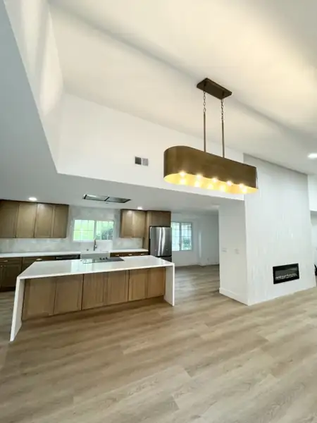 Kitchen island with brass linear pendant and fireplace wall