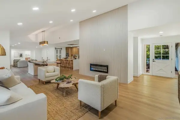 Living room with fluted fireplace wall and front entry