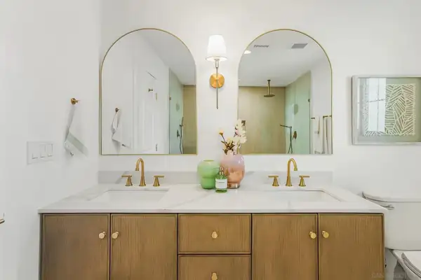 Double vanity with arched brass mirrors