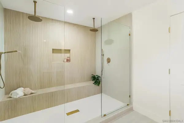 Walk-in shower with fluted tile, bench and brass rain heads