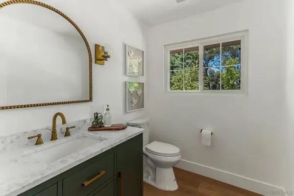 Powder room with green vanity and arched mirror
