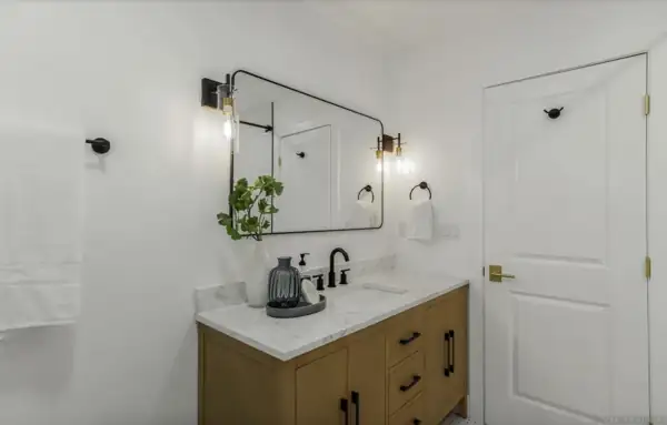 Bathroom vanity with black-framed mirror and sconces