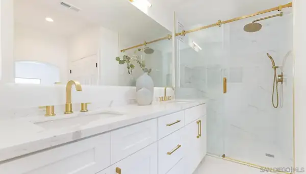 Bathroom with white double vanity and brass shower fixtures