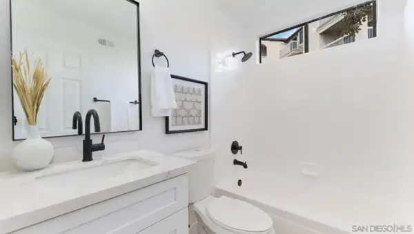 Bathroom with black fixtures and white tile tub surround