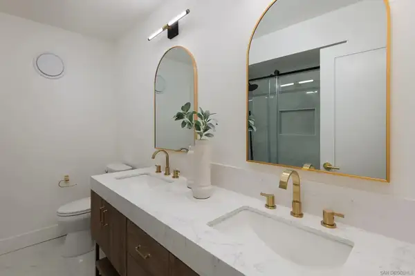Bathroom with double vanity and arched brass mirrors